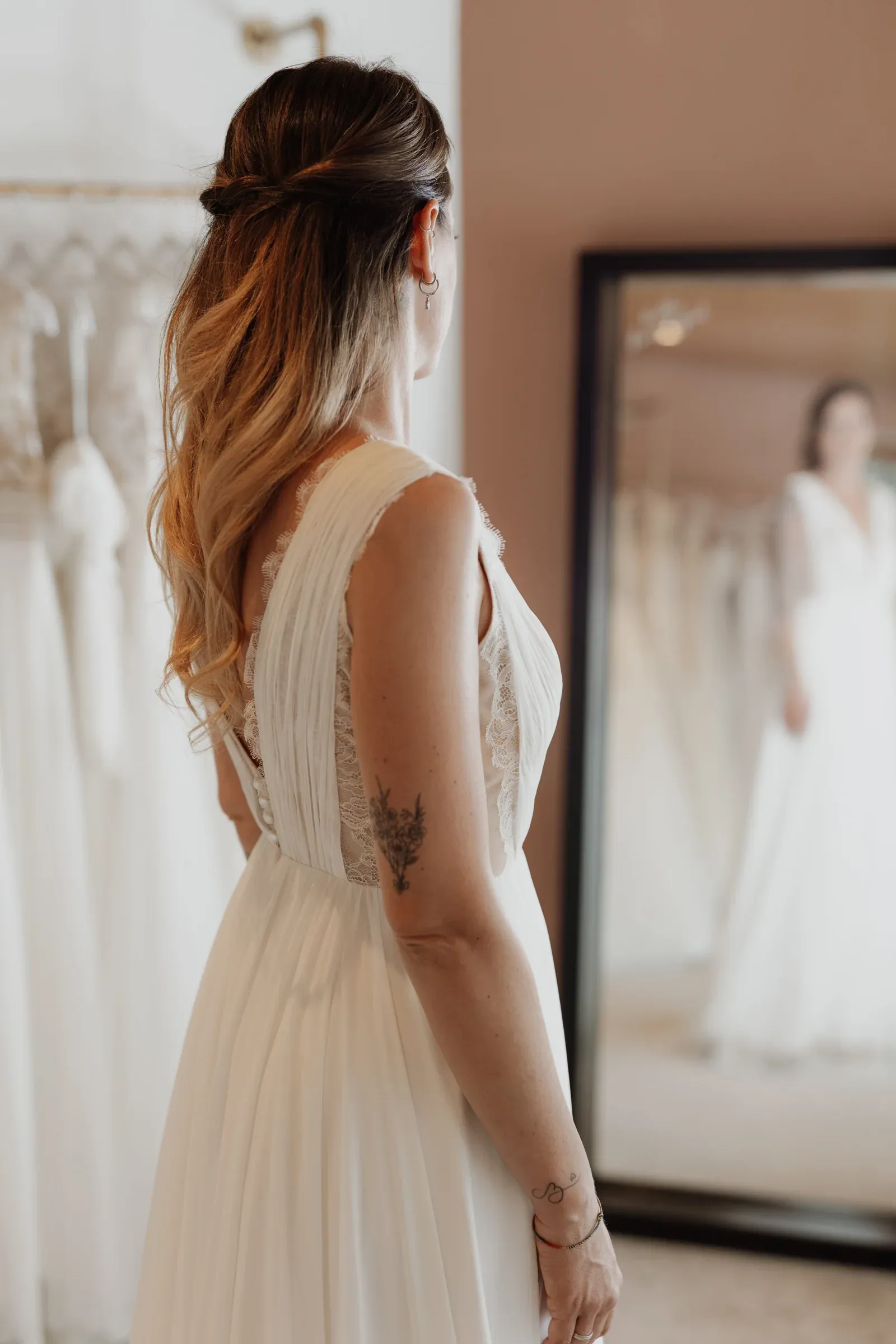 Braut betrachtet ihr Spitzenkleid im Spiegel des Wertvoll-Ateliers.