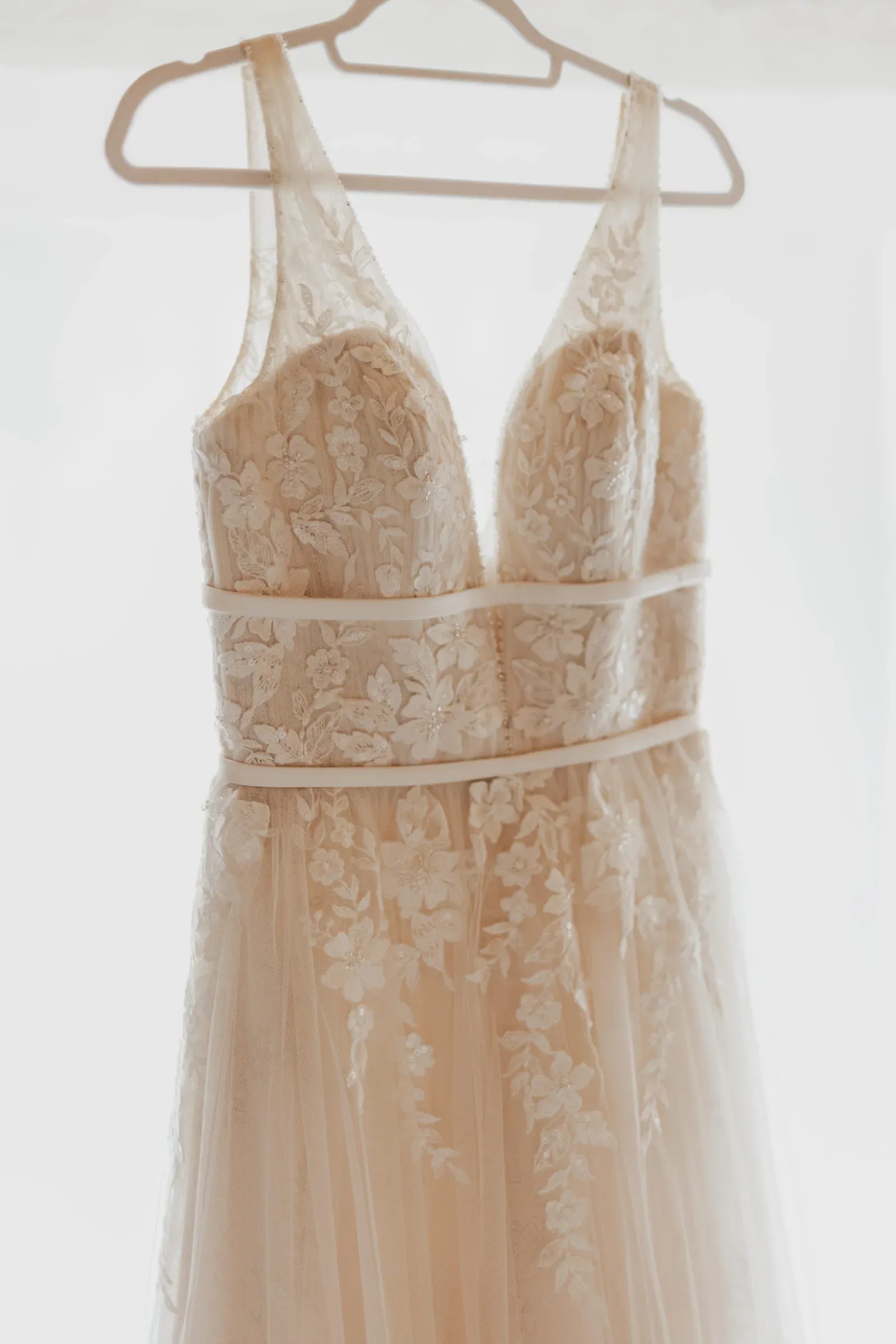 Ungetragenes Brautkleid hängt ausgewählt an einem Kleiderbügel.