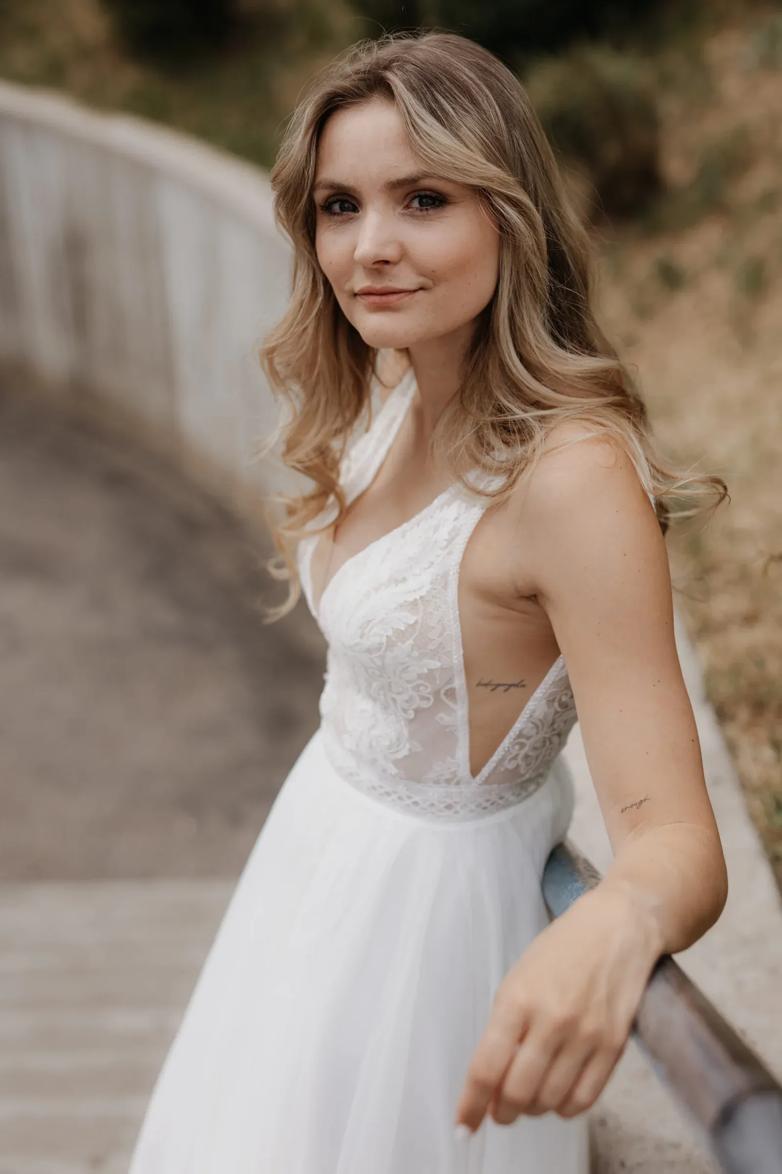 Braut im Spitzenkleid bei einem natürlichen Outdoor-Portrait.
